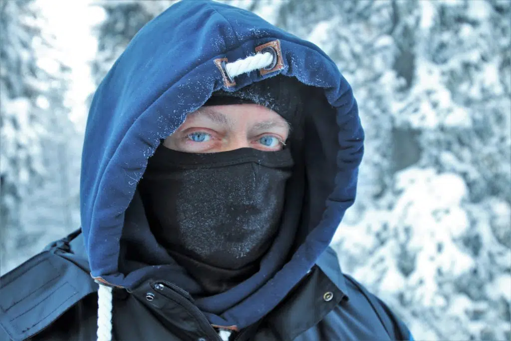 Photo of a man in the mountains, covering his entire face, except the eyes. 