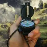 Image of a hand holding a compass on a foggy landscape.