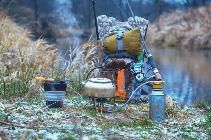 Outdoors scenario with cooking equipment in front of a bushcraft backpack. 