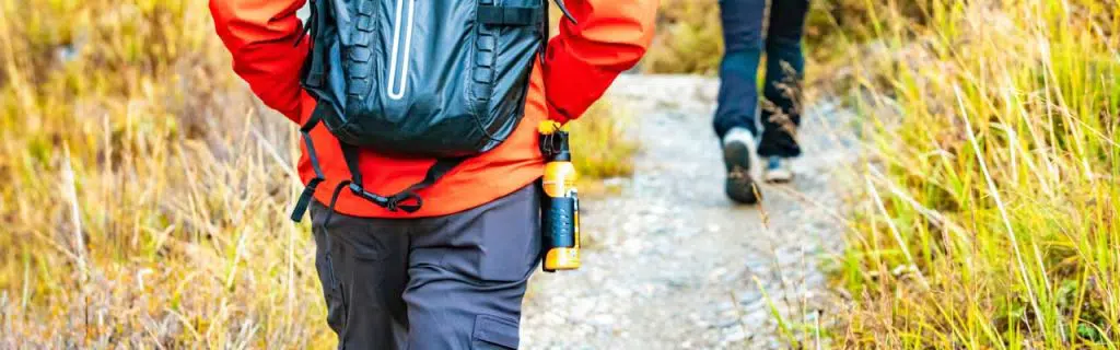 Photo of bear spray hung on the belt of a hiker.