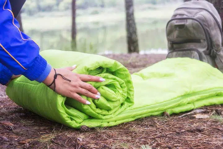 A woman folds and packs a sleeping bag, going on a journey through the forest. 