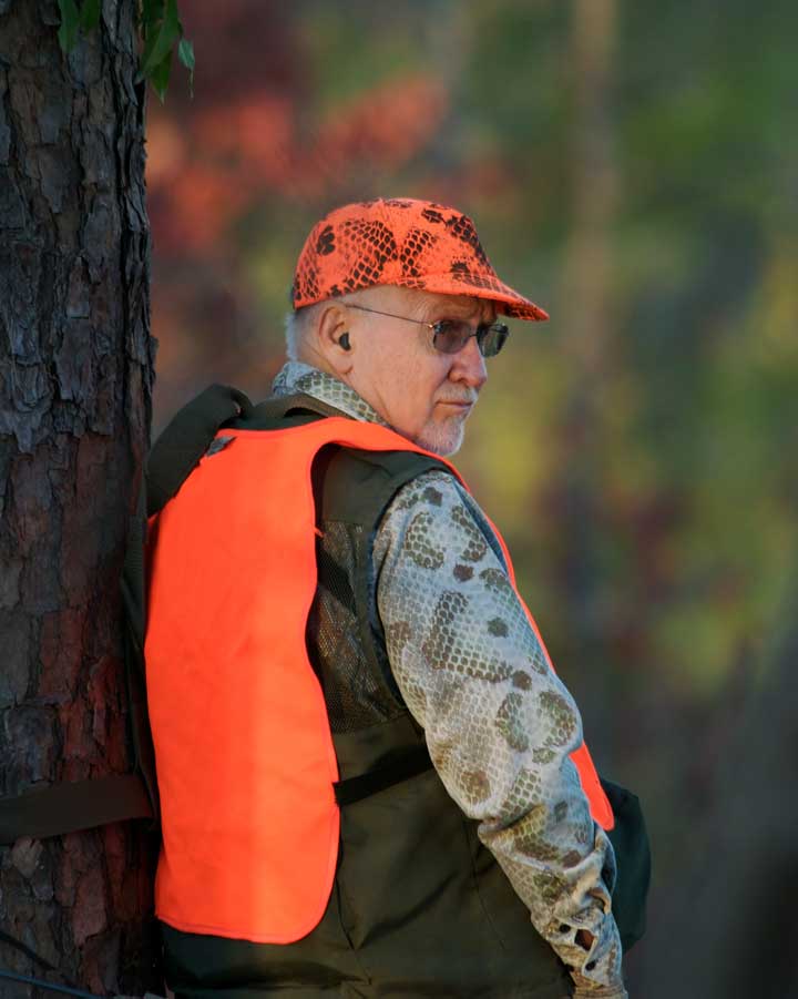 A deer hunter standing in his tree stand to stretch his legs. 