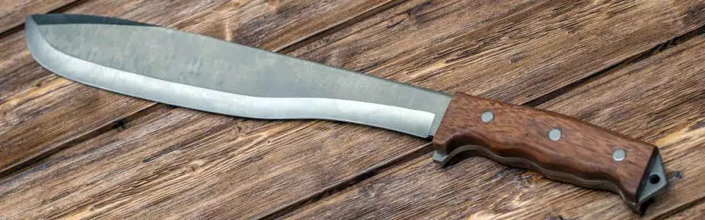 Machete for cutting grass on brown wooden background