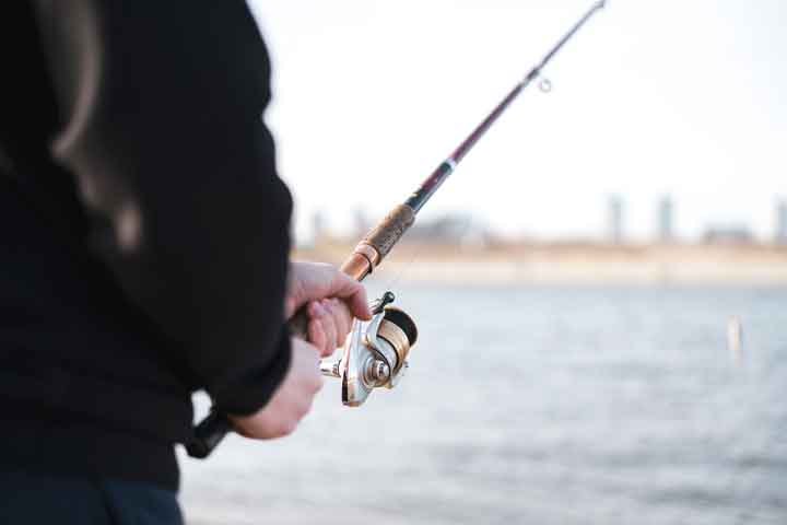 male person holding a fishing rod with bait