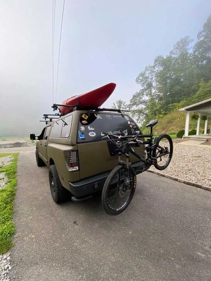 Truck carrying a kayak on the roof rack, and a bicycle on the back.