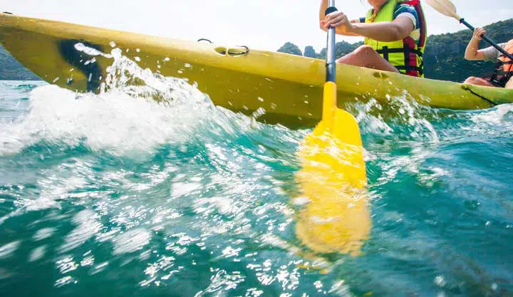 explorer women in life jacket paddling hard the kayak with splashes. 