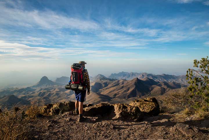 A man pauses at the top of a steep cliff overlooking the Mexican border in Big Bend National Park, Texas