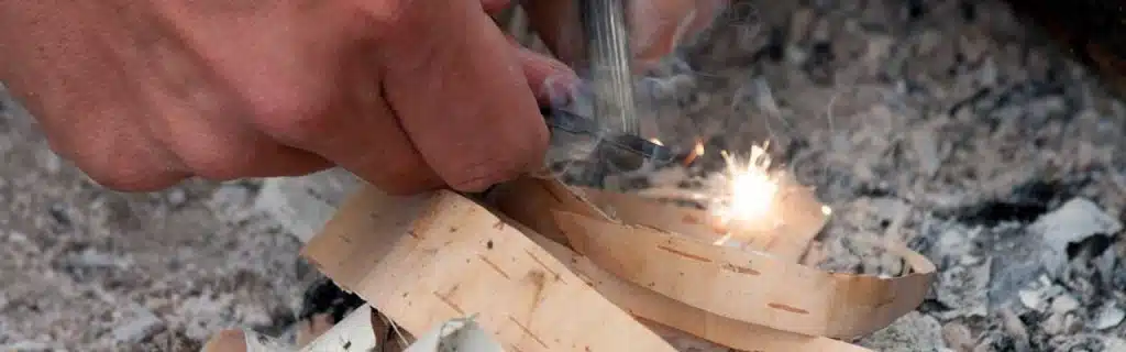 Lighting birch bark with a flint and steel.