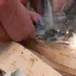 Lighting birch bark with a flint and steel.