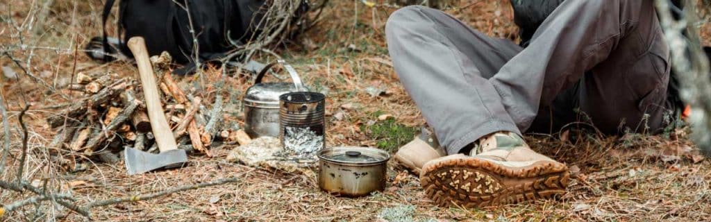 man relaxing in the forest camping, near the wood stove, utensils and axe with firewoods.