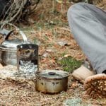 man relaxing in the forest camping, near the wood stove, utensils and axe with firewoods.