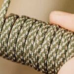 Girl ties a knot in the rope as part of her beginner bushcraft project.