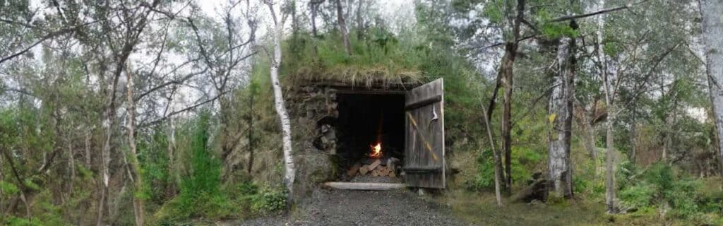 Photo of a bushcraft shelter with fireplace inside, in the middle of the woodlands.