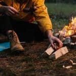 A lonely wanderer is having dinner in the mountains by a campfire.